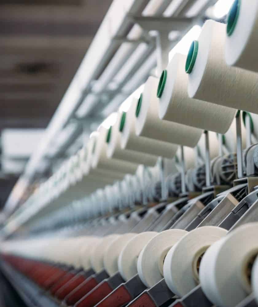 An industrial machine showcasing a large collection of white yarn spools, organized for efficient textile processing.