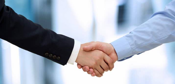Image of a firm handshake  between two colleagues in office.
